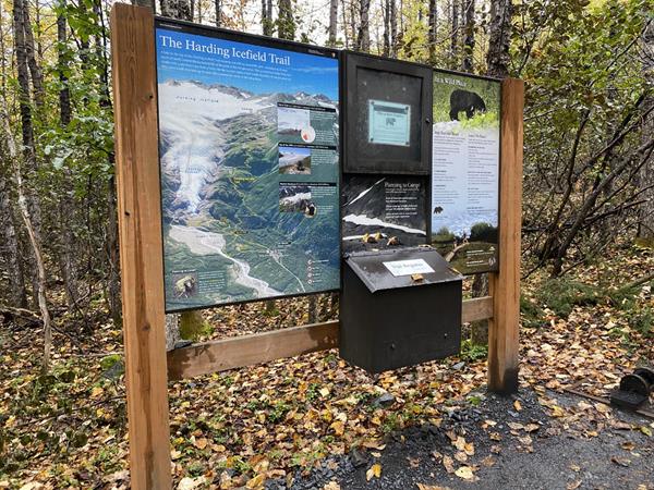 An information sign at the start of the Harding Icefield Trail. A forest is behind the sign.
