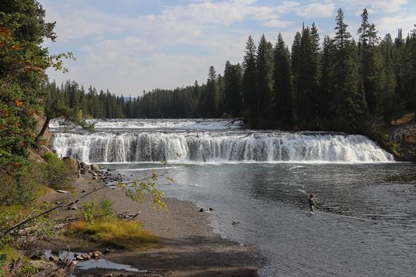 A waterfall cuts across a broad river.