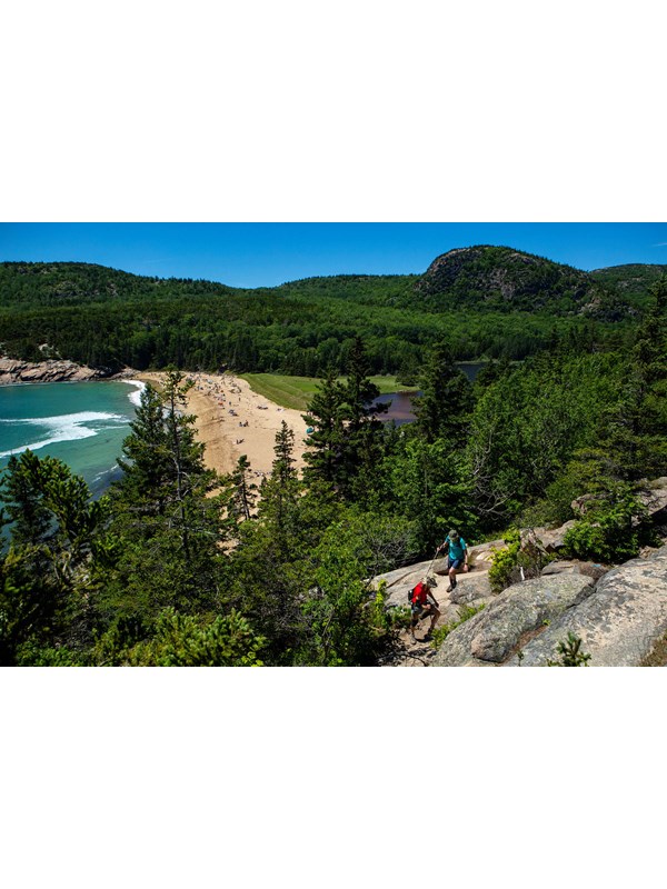 Two hikers walk along Great Head Trail overlooking Sand Beach.