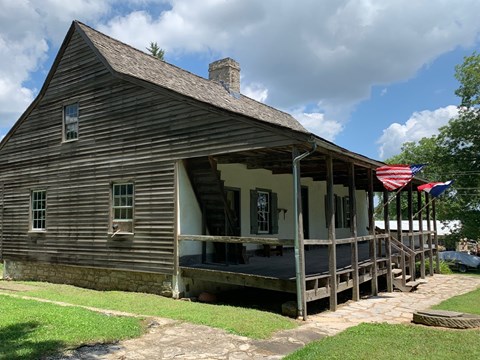 A historic home with a large front porch on which the American and French flags are flying