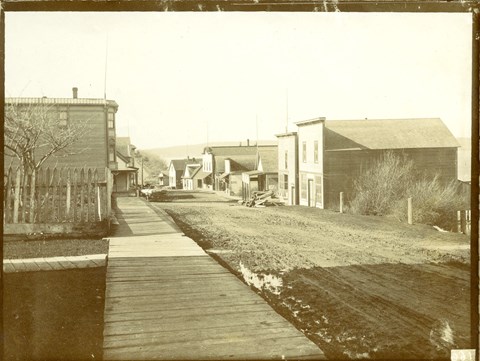 Old buildings with a dirt road and wooden boardwalks.