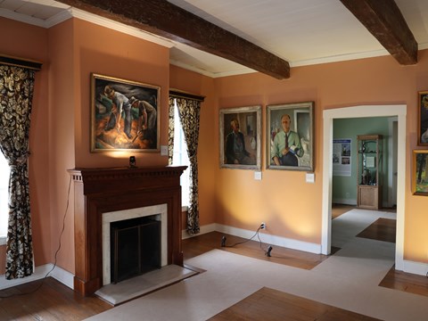 A room filled with paintings hanging on the walls and a fireplace.