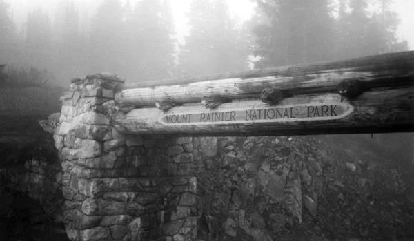 A black and white photo of a log bridge with stone abutments.