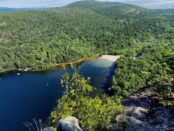 Echo Lake and Beach are nestled at the bottom a mountain ridge while granite cliffs rise steeply.