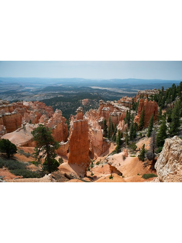A landscape of red rocks in the foreground with hazy mountains on the horizon