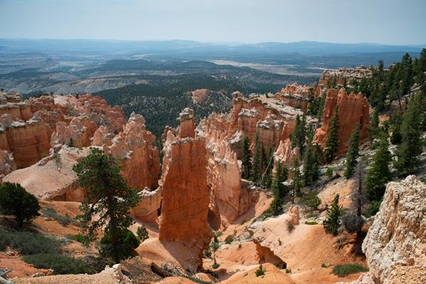 A landscape of red rocks in the foreground with hazy mountains on the horizon