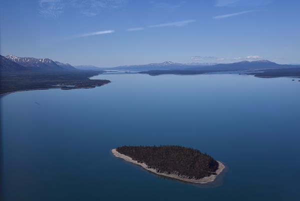 An aerial view of an island in the blue waters of Lake Clark