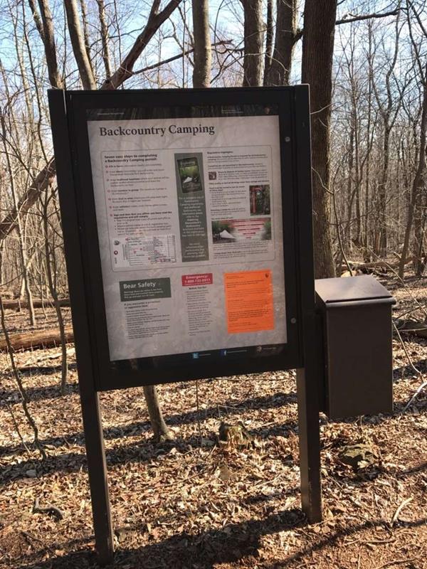 A small, angled roof supported by two brown, vertical beams shelters a large, flat glass case.