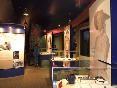 You can see three glass cases with artifacts inside and portraits next to them.