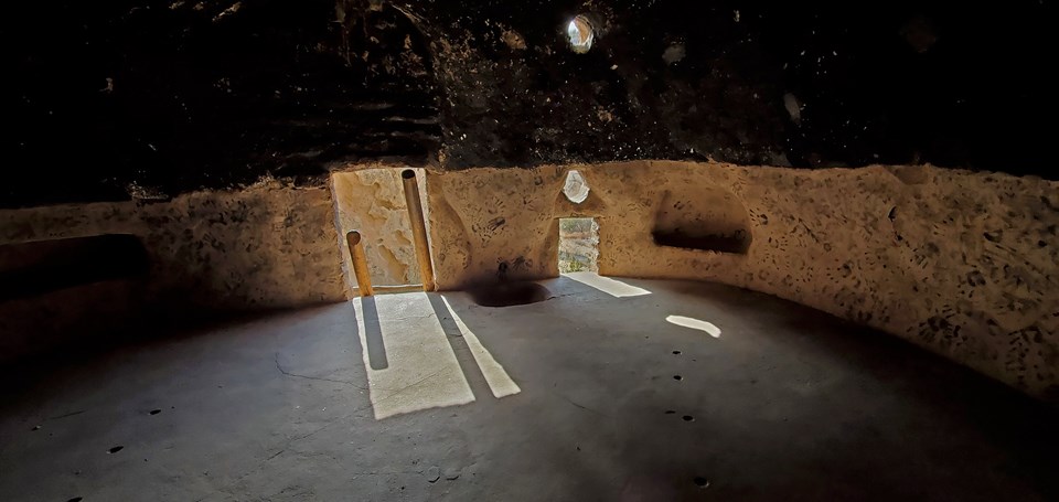 multiple opening let light into a dark space, through one opening a ladder can be seen