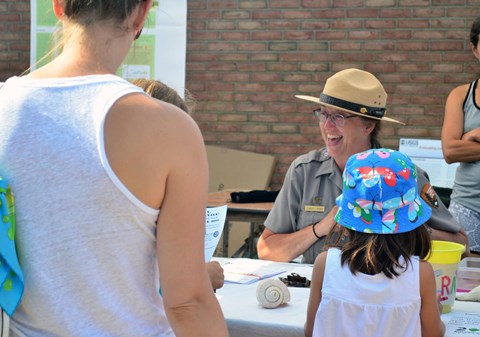 Park ranger gives out Junior Ranger badge to young visitor.