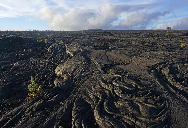 A lava field with a distant lava shield at sunset