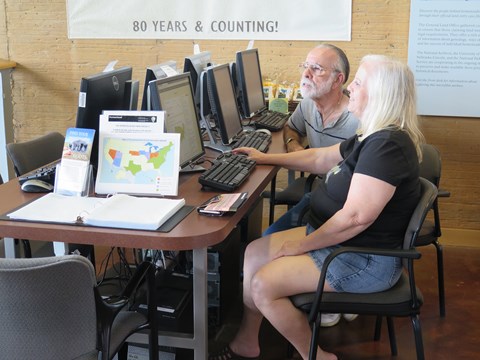 Two people sitting down and looking at records on computers