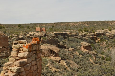 a crumbling stone wall in the foreground, with other stone structures across the canyon.