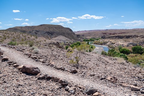 A trail winds above on a high vista overlooking a small stream.