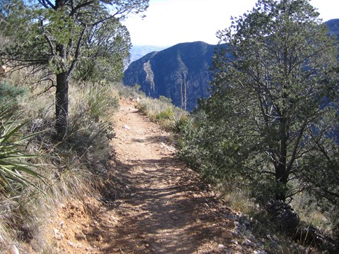 A trail cuts through a desert mountain landscape.