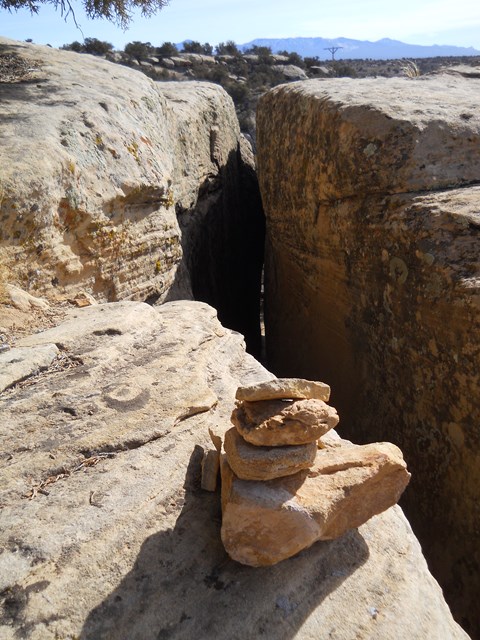 A stack of rocks by the entrance of a thin pathway through the rock