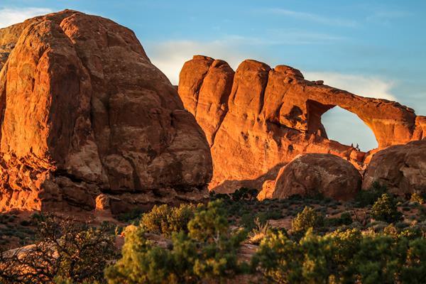 A large sandstone arch is visible at sunset