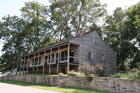 A large vertical log home with a wraparound porch.