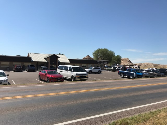 Several vehicles parked in front of a tan building with a Cedar Pass Lodge sign