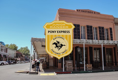 A junior ranger badge on the picture of a historic wooden building.