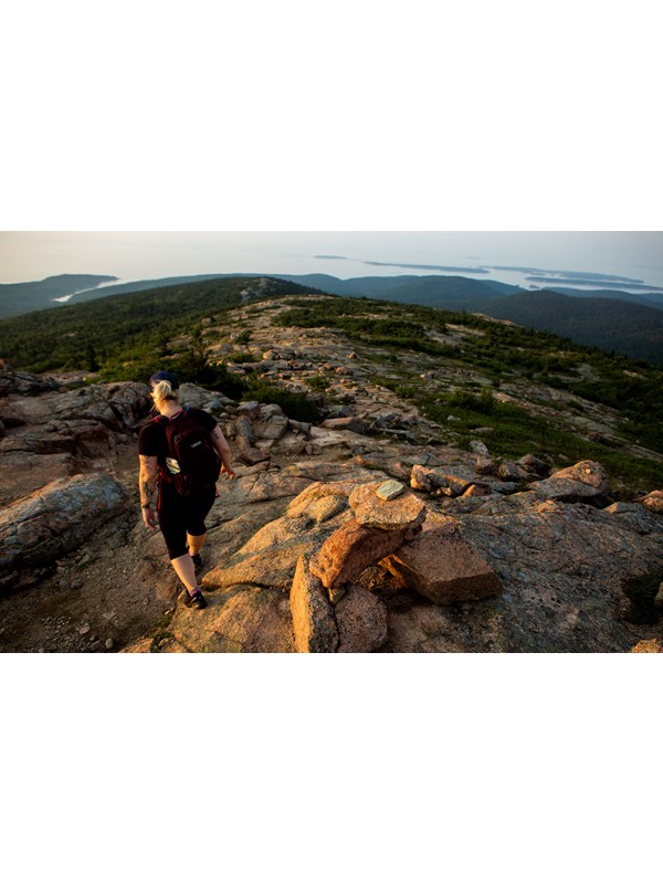 Visitor hikes down granite trail marked with cairns