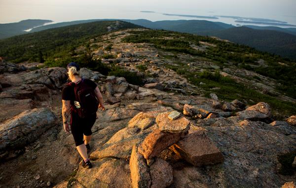 Visitor hikes down granite trail marked with cairns