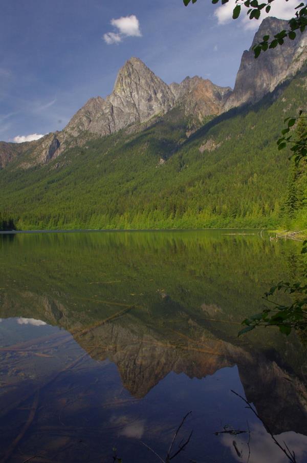 A clear blue lake in front on forested shores and a mountain.