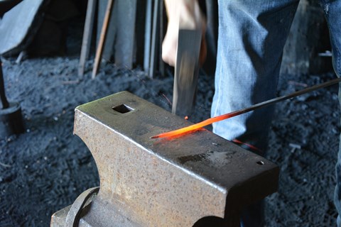 Metal rod with red tip on top of anvil.
