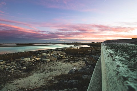 pink and purple sunrise next to seawall and river