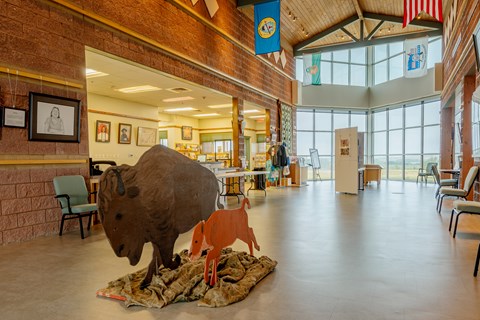 A large gallery with a high cathedral style ceiling, red stone walls, and wooden bison.