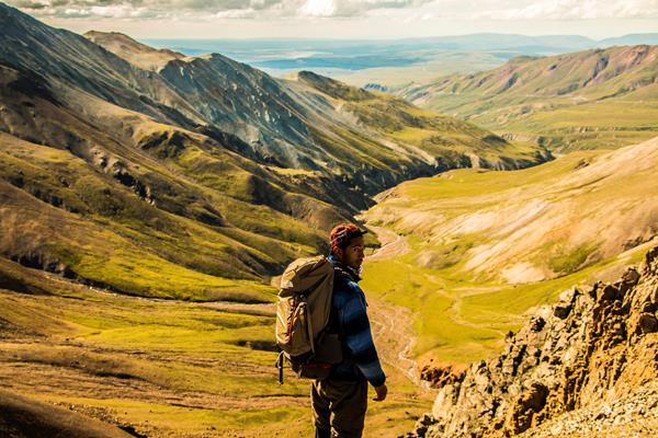 a man standing on a ridge top with a large backpack on