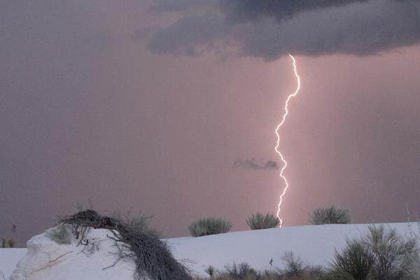 Bolt of lighting strikes white sand dune