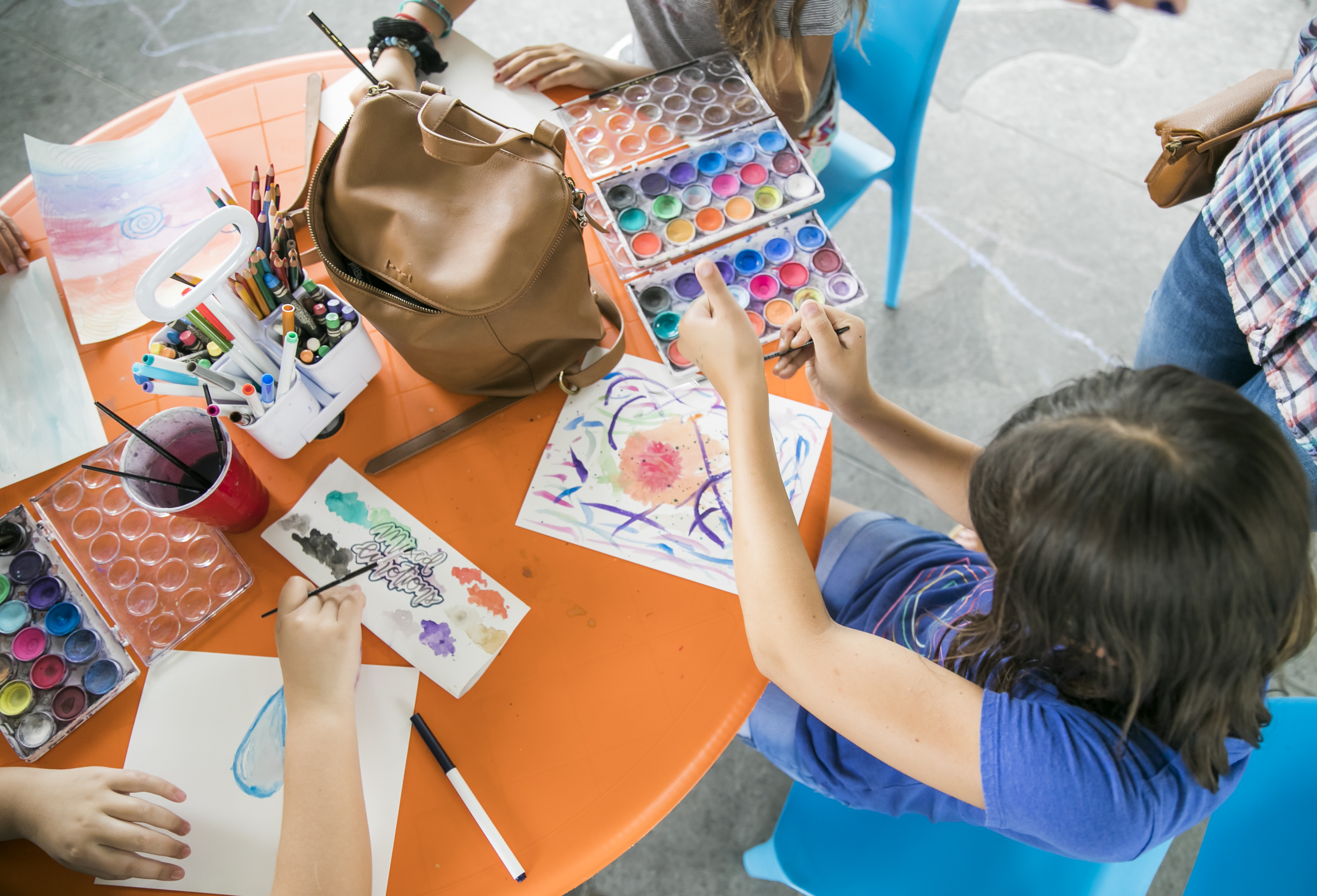 a child sitting at a craft table working on watercolors