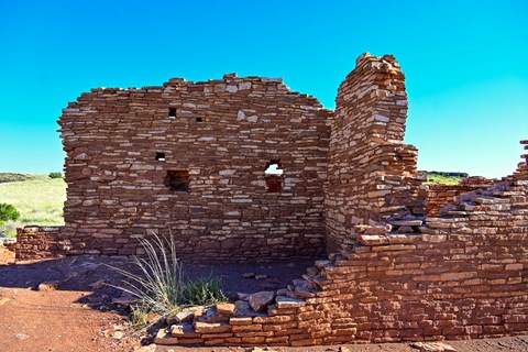 A red and tan sandstone pueblo is set against a deep blue sky