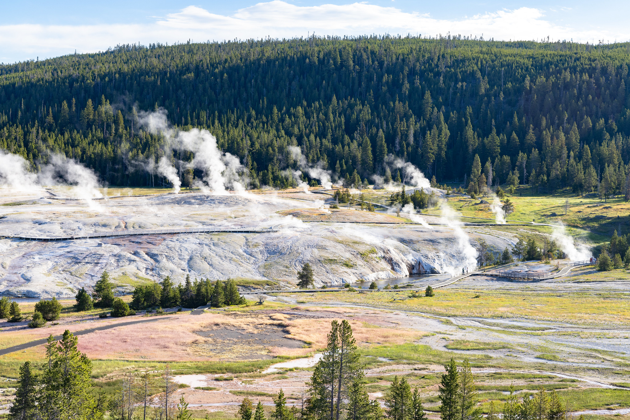 Steam rises from thermal features located on a barren hill in a hydrothermal basin.