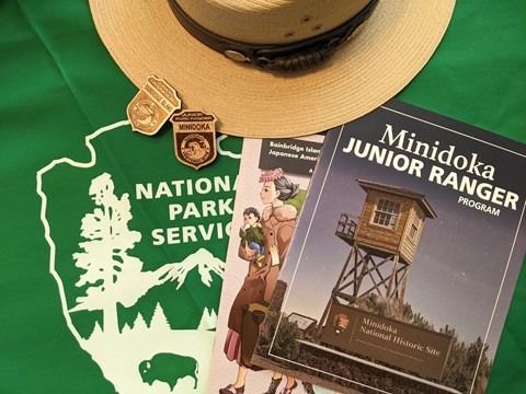 Junior Ranger booklets and badges on a table with a ranger hat and a National Park Service symbol.