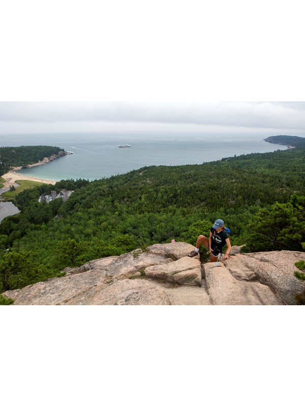 person climbing up rocks with a ocean view in the distance