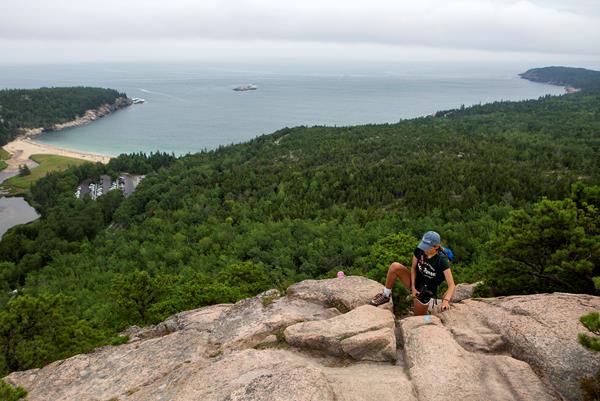 person climbing up rocks with a ocean view in the distance