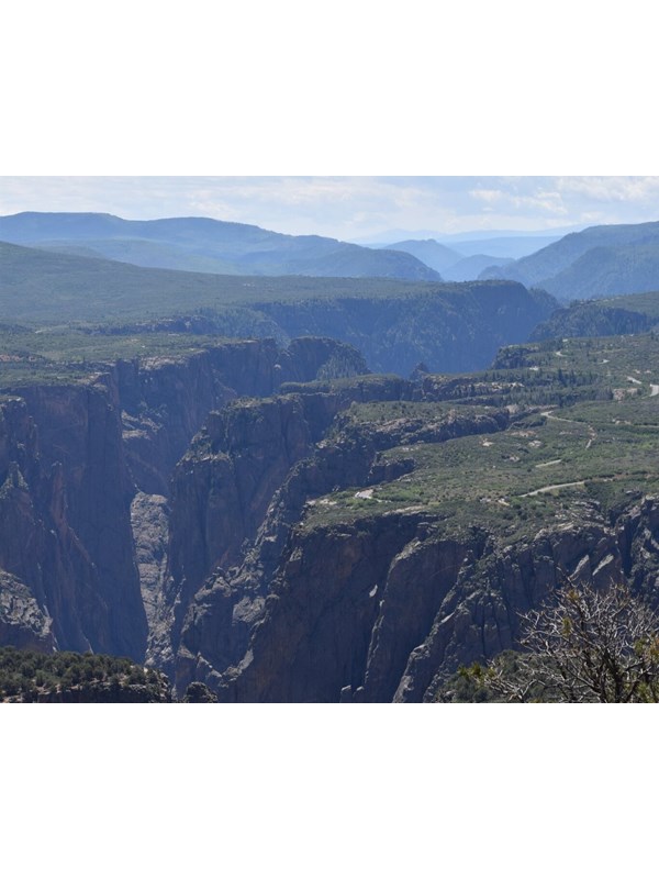 Green and blueish canyon cliffs with mountains in the background