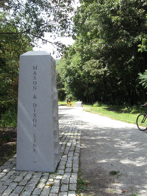 a granite obelisk next to a ten-foot wide crushed stone pathway