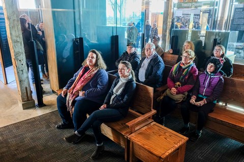 Visitors sit in a small theater seating area inside the Minidoka Visitor Center.