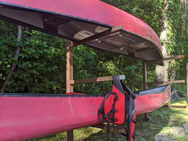 Two canoes sitting on a rack with a PDF hanging.