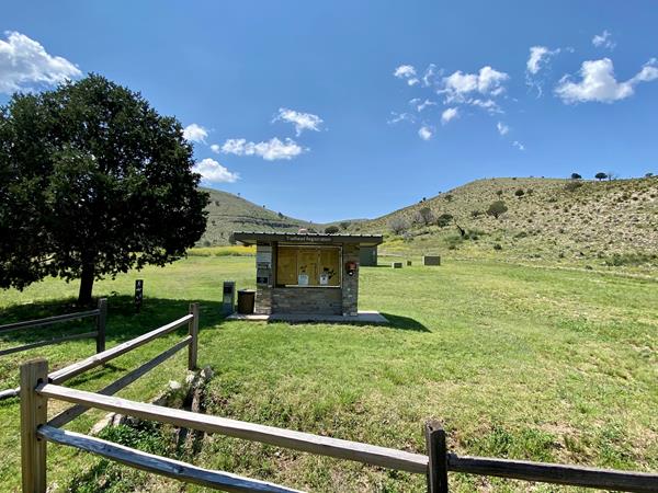 Stone kiosk with trail information at the head of a meadow area