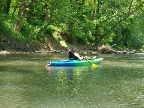 A child paddling a kayak along a river