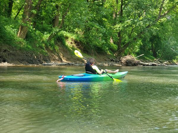 A child paddling a kayak along a river
