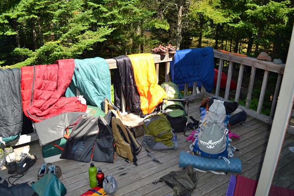 Scattered camping gear hangs to dry on a porch after a backpacking trip.