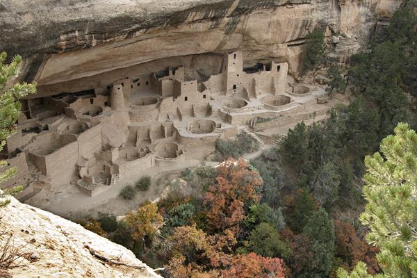 A view down at an ancestral stone-masonry village in a sandstone alcove surrounded by trees