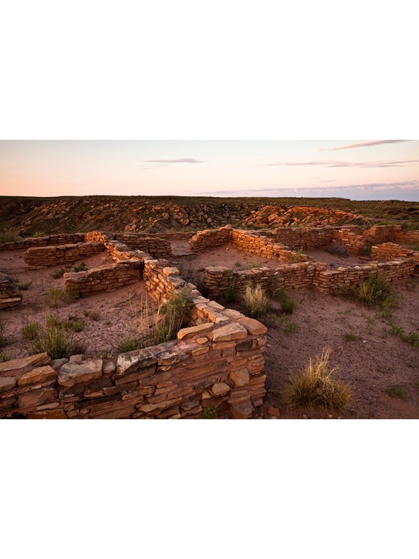 Archeological site with remnants of masonry walls in late afternoon light.