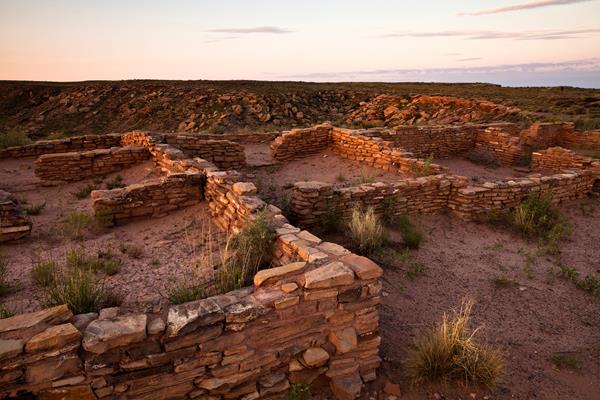 Archeological site with remnants of masonry walls in late afternoon light.